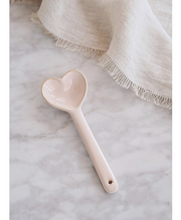 Load image into Gallery viewer, Blush-colored ceramic spoon with a heart-shaped scoop, on marble countertop with linen napkin
