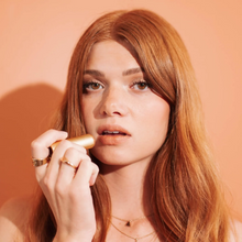 Load image into Gallery viewer, Young woman with copper hair applying a matching copper lip tint
